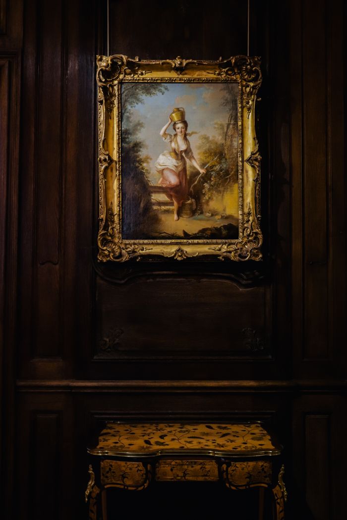 Elegant framed painting displayed in a dimly lit Paris gallery.